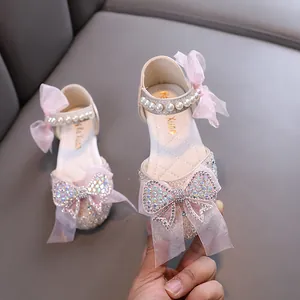 Elegant pink girls princess shoes featuring a large rhinestone bow and pearl straps