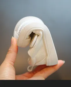 Close-up detail of flexible soft sole baby white canvas indoor shoes for kindergarten.