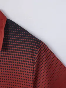 Close-up of red men's polo shirt with black polka dot print pattern and breathable fabric texture