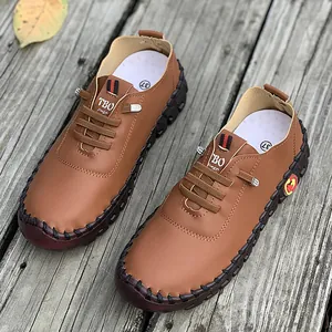 Women's handmade brown loafers with soft sole and decorative laces on wooden planks.