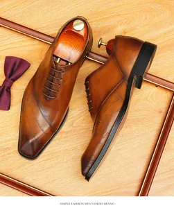 Dettaglio ravvicinato di scarpe Oxford in pelle marrone con elegante incisione e stemma