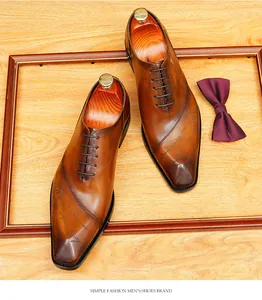 Dettaglio di scarpe Oxford in pelle marrone con motivo artistico e design a punta sottile.