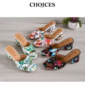 Detaillierte Ansicht von Damen-Sandalen mit Blumen-Graffiti und hohem Absatz auf Holz.