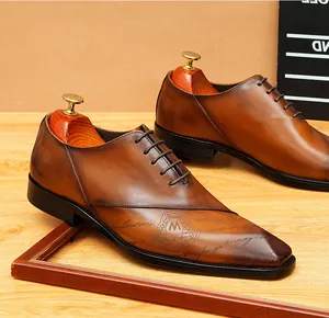 Dettaglio di scarpe Oxford in pelle marrone con incisioni e punta elegante.