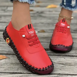 Detailed view of red handmade soft sole flat loafers for women on a wooden background