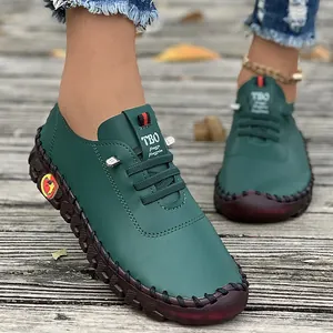 Detail shot of green handmade flat shoes with soft rubber soles on wooden deck