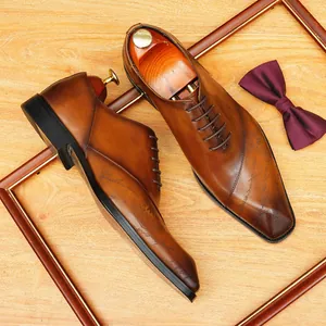 Classiche scarpe Oxford da uomo in pelle marrone con eleganti incisioni e punta a punta.