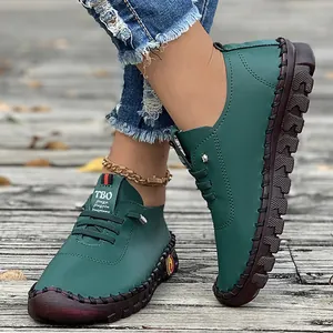 Close-up view of green handmade leather shoes featuring soft brown soles and laces