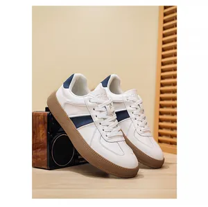 Detailopname van witte leren GAT-sneakers met marineblauwe accenten en rubberen zool