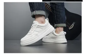 Detail view of men's white leather casual sneakers with thick sole and side texture