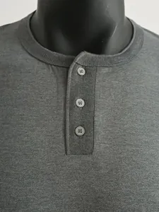 Detailopname van de knoopsluiting en de geribbelde halslijn van een grijs Henley-shirt.