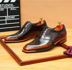 Primer plano de zapatos Oxford marrón con punta cuadrada y detalles en suela naranja.