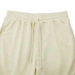 Close-up of men's cream casual pants with elastic waistband and drawstring detail.