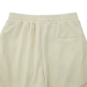 Close-up of cream retro slim men's casual pants showing elastic waist and back pocket.