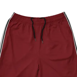 Detail van bordeauxrode sportbroek voor heren met zwart trekkoord en strepen op de zijkant.