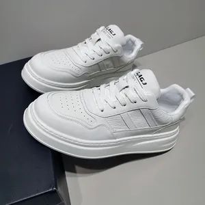 Close-up of men's white leather platform sneakers with breathable design on grey background.