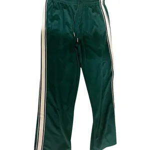 Close-up detail van de donkergroene heren joggingbroek met contrastrerende zijstrepen.