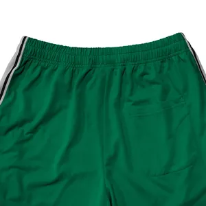 Detail van de taille en achterzak van een groene sportbroek met modieuze zijstrepen.