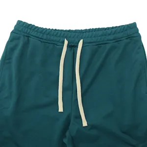 Detail of teal men's trousers featuring elastic waistband and white drawstrings.