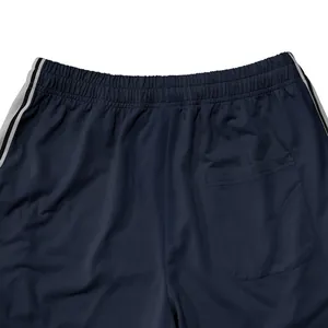 Detailopname van de tailleband van een donkerblauwe heren sportbroek met zijstrepen