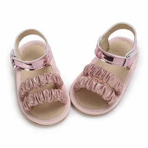 Detalle de sandalias rosa para bebé con elegantes tiras de volantes y banda metálica
