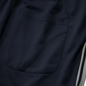 Detailopname van de zak en zijstrepen op de donkerblauwe herensportbroek voor heren.