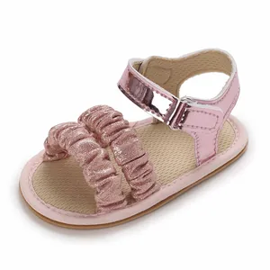 Vista detallada de sandalias rosas para bebé con volantes brillantes y cierre de velcro.