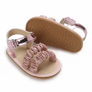 Detalle de sandalias de bebé con purpurina rosa que muestra la suela de goma suave.