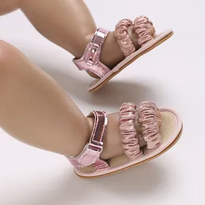 Primer plano de sandalias rosas para bebé con correas de volantes y suela suave