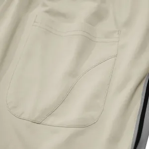 Gedetailleerde opname van zak en zijstreep op een beige heren sportbroek