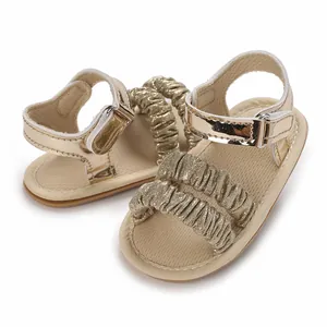 Primer plano de sandalias doradas para bebé niña con correas de volantes y suela de goma