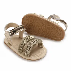 Detalle de sandalias doradas para bebé con suela de goma blanda y tiras con purpurina