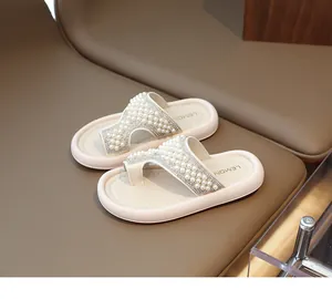 Detalle de sandalias crema para niños con adornos de perlas y pedrería