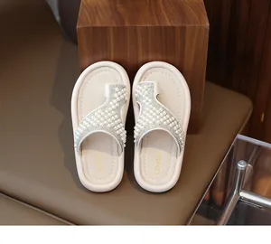 Vista detallada de chanclas elegantes para niña en color crema con perlas blancas.