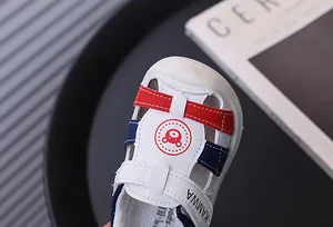 Detalle de sandalias blancas para bebé con logo de oso rojo y detalles en azul