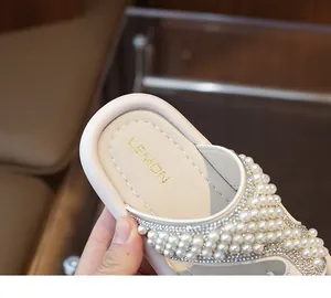 Primer plano detallado de los elegantes adornos de perlas blancas y pedrería en sandalias niña.