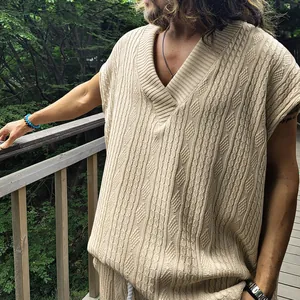 Vue détaillée d'un gilet en maille beige à col en V avec des motifs de torsades complexes