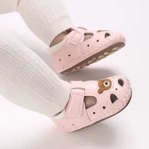 Primer plano de sandalias de verano rosa para bebé con parche de oso y diseño transpirabile.