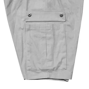 Detailed macro view of a functional cargo side pocket with metal buttons on gray shorts