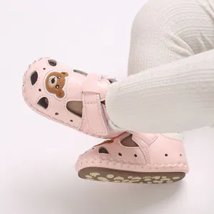 Primer plano de sandalias rosas para bebé con parche de oso y diseño calado