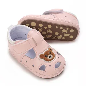 Primer plano de sandalias rosas para bebé con parche de oso y diseño calado