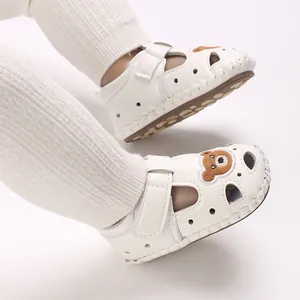 Primer plano de sandalias blancas para bebé con bordado de oso y diseño aireado