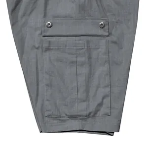 Close-up of grey cargo shorts featuring textured fabric and dual snap-button pocket detail.
