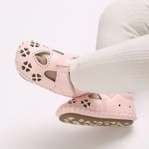 Gedetailleerd beeld van roze babysandalen met hartpatronen en flexibele zool