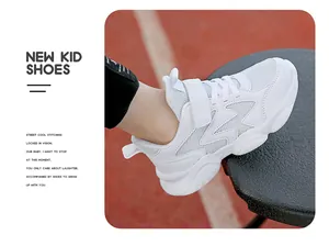 Side view of white children's chunky sneaker with velcro strap on a running track