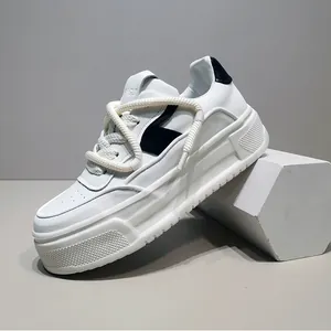 Κοντινό πλάνο ανδρικών λευκών sneakers με πλατφόρμα, χοντρά κορδόνια και μαύρες πινελιές.