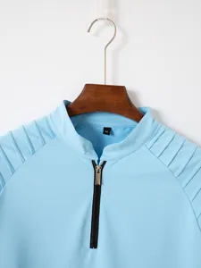 Close-up detail of light blue men's polo shirt with zipper neck and shoulder pleats