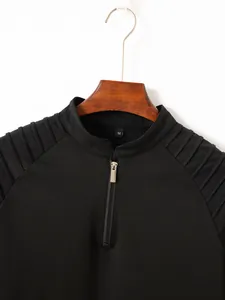 Close-up of black men's polo shirt featuring a metal zipper and pleated shoulder detail.