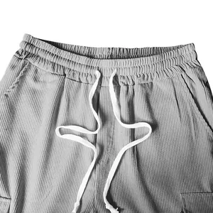 Vista dettagliata della vita elastica e dei cordoncini bianchi sui pantaloni di velluto grigio