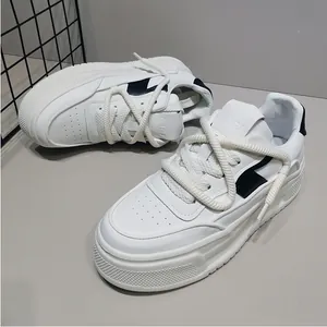 Λεπτομερής προβολή ανδρικών λευκών chunky sneakers με χοντρή σόλα και μαύρες λεπτομέρειες.